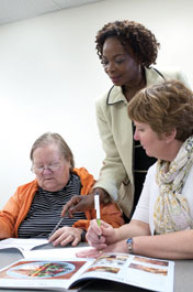 Ade Olomu (center) and project manager Annette Sokolnicki (right) review medications with a patient.