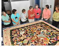 Members of the Michigan Quilt Network view quilts from the MSU Museum's quilt collection. Folk arts curator Marsha MacDowell (far right) and collections assistant Beth Donaldson (next to MacDowell) explain that the quilt was made by Lois Darcus, of Elsie, Michigan, between 1876 and 1900.