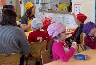 Renee Clark sits with her students while sampling a variety of fruits and vegetables.