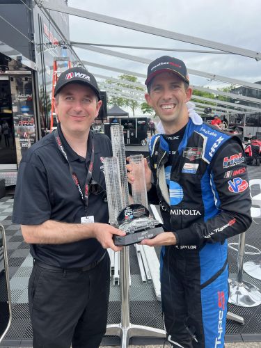 David Ferguson and Ricky Taylor pose with a trophy in the International Motor Sports Association garage area at the Detroit Grand Prix.
