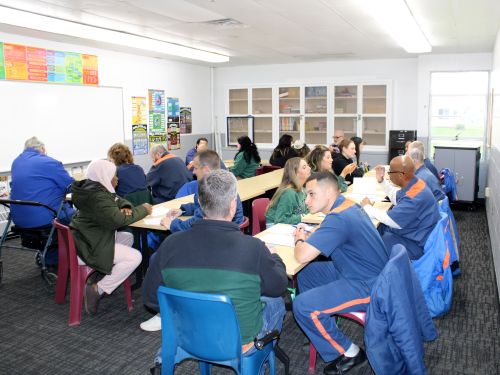 MSU students and incarcerated college students work on writing projects at tables in a classroom at Parnall Correctional Facility.