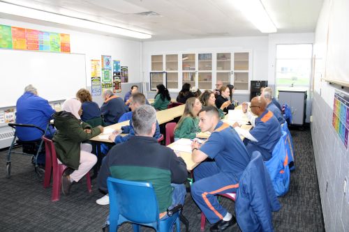 MSU students and incarcerated college students work on writing projects at tables in a classroom at Parnall Correctional Facility.