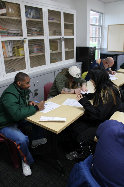 Participants in a poetry workshop sit around a table in a classroom at Parnall Correctional Facility