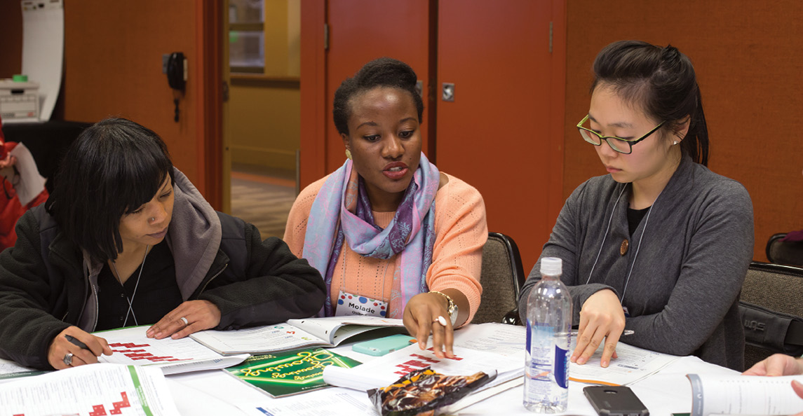 Oyemolade Osibodu (center) works with attendees at a conference hosted by the Connected Mathematics Project (CMP).
